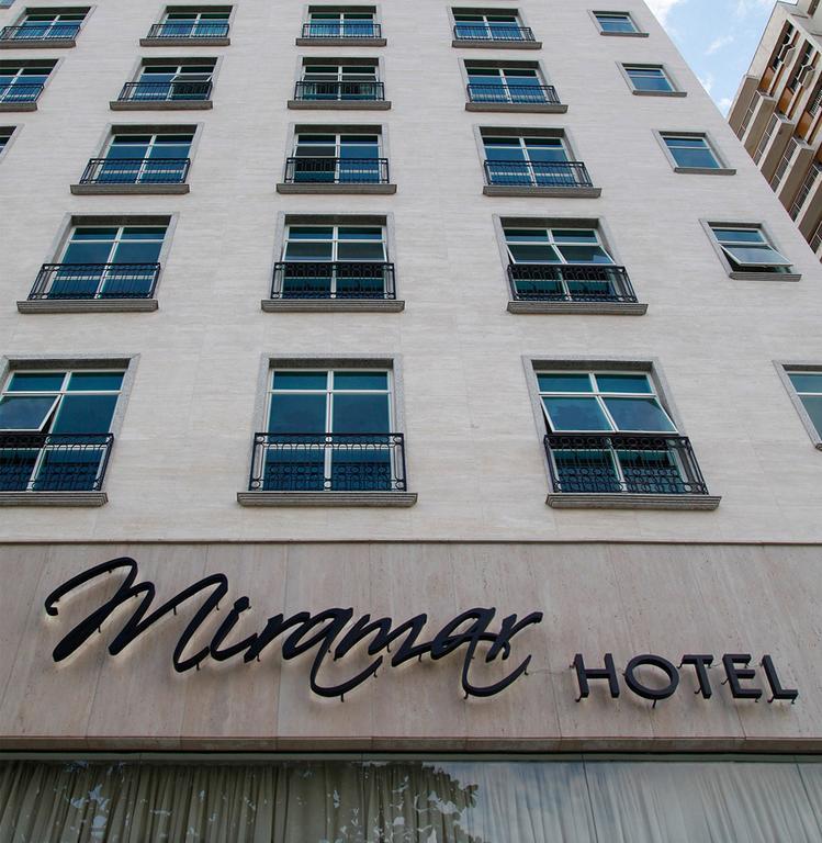 فندق ميرامار باي وندسور ريو دي جانيرو المظهر الخارجي الصورة The image shows the exterior of a hotel building. The hotel is named "Miramar HOTEL," with the name displayed prominently in a stylish font. The facade features several large windows with balconies, which are uniformly arranged. The overall design ha